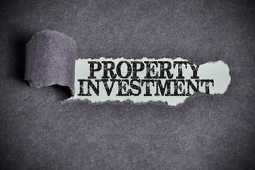Fototapeta premium property investment word under torn black sugar paper