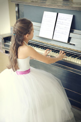Attractive little princess girl plays piano