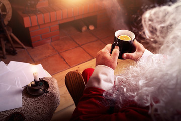 Santa Claus rests in hut with a fireplace and hot tea with lemon