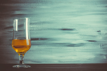 Glass with cognac on wooden background. Vintage style. Toned image.