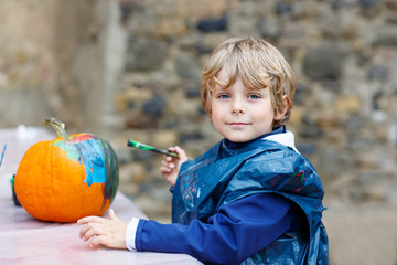 Little kid boy painting with colors on pumpkin © Irina Schmidt