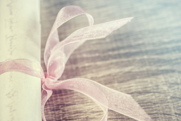 Vintage wedding invitation with pink ribbon and a red heart. Cross processed image with selective focus