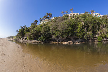 Fototapeta na wymiar Beach River Lagoon rocky cliffs apartments landscape