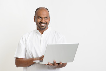 Mature Indian man using laptop looking at side