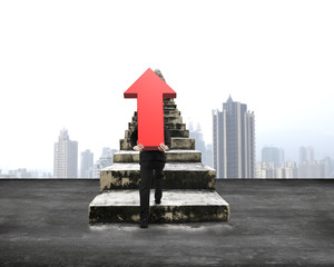 Man carrying red arrow up climbing concrete stairs