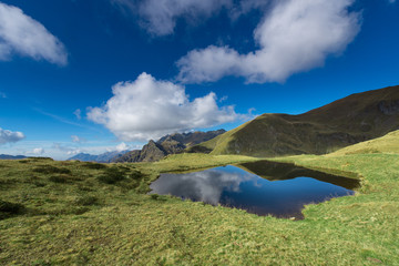 Small mountain lake in the middle of meadows