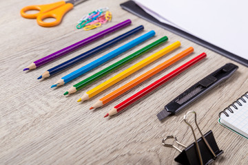 Paper, pencils, brush, green apple on wooden table