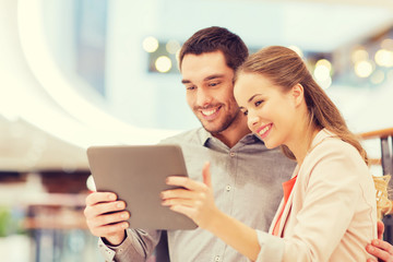 happy couple with tablet pc taking selfie in mall