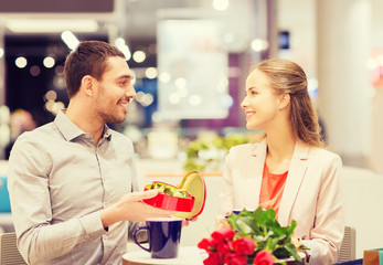 happy couple with present and flowers in mall