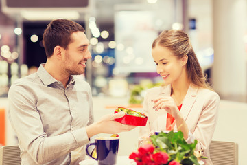 happy couple with present and flowers in mall