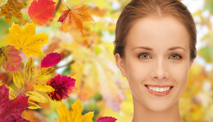 beautiful young woman face over autumn leaves