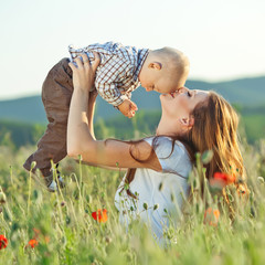 beautiful happy mother with her baby in a green field 