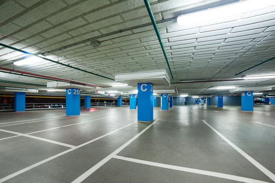 empty grey parking with colored blue columns without cars