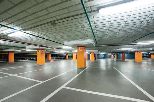 empty grey parking with colored orange columns without cars