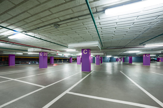 empty grey parking with colored violet columns without cars