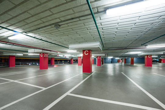 empty grey parking with colored red columns without cars