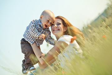 beautiful happy mother with her baby in a green field 