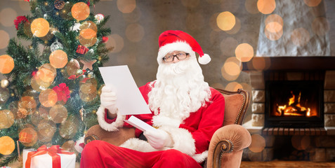 santa claus reading letter in armchair at home