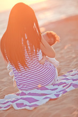 Happy mother with her son are resting on evening beach