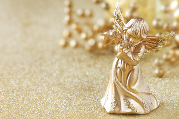 Christmas angel playing a flute at golden background