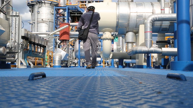 Engineer walking on steel plate form in process area of chemical plant 