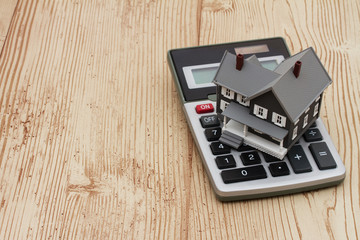 A gray house and calculator on wood background