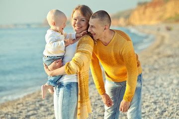 Happy family are playing with son on the beach 
