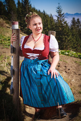 Portrait einer jungen dicken Bäuerin in den Bergen in Festtagstracht und großer Oberweite, mit...
