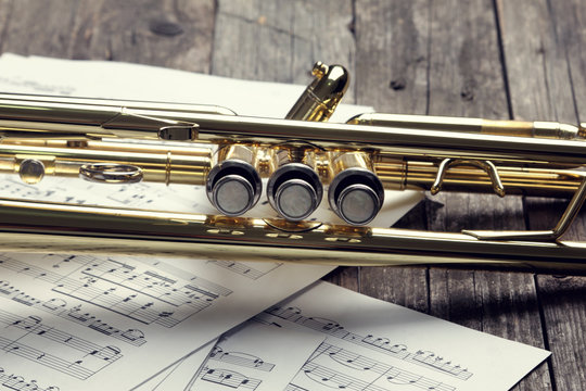 Trumpet and sheet music on old wooden table. Vintage style.