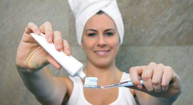 Woman Hands Holding Toothbrush And Placing Toothpaste On It