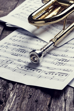 Trumpet and sheet music on old wooden table. Vintage style.
