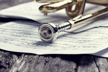 Trumpet and sheet music on old wooden table. Vintage style.