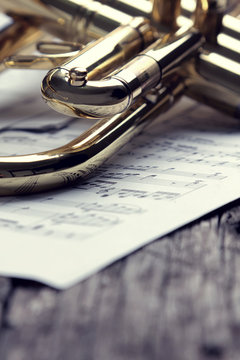 Trumpet and sheet music on old wooden table. Vintage style.
