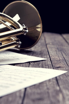 Trumpet and sheet music on old wooden table. Vintage style.