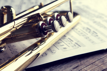 Trumpet and sheet music on old wooden table. Vintage style.
