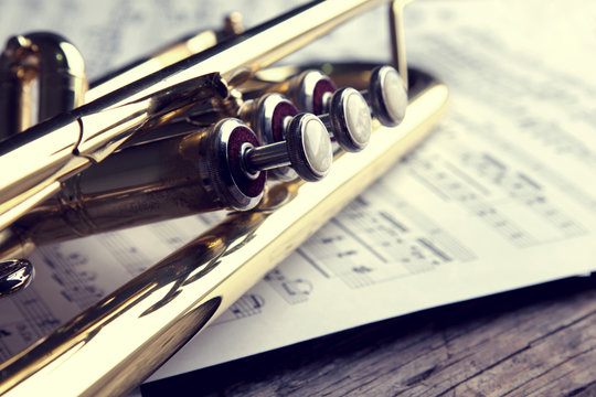 Trumpet and sheet music on old wooden table. Vintage style.