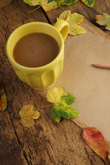 notebook and coffee on wooden table decorated with autumn leaves
