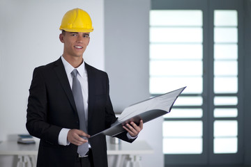 Successful businessman with yellow helmet holding a folder and l