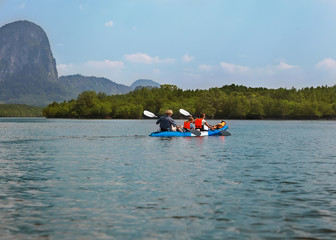 family sailing kayaking among the rocks by the sea