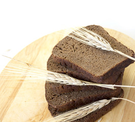 Slices of rye bread on a wooden board and ears of rye