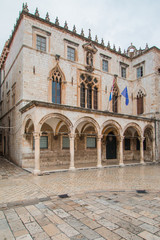 Fototapeta na wymiar Sponza Palace in Dubrovnik with flag of Croatia and European Union. Sponza Palace was built in 16th century. 
