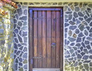 Stylish wooden door with metal ornaments on stone wall