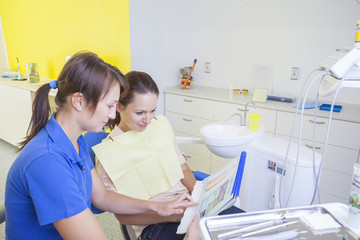Female dentist showing her patient an information sheet