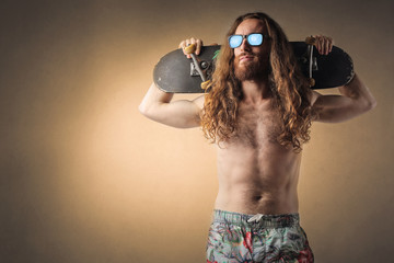 Long-haired man carrying a skateboard on his shoulders