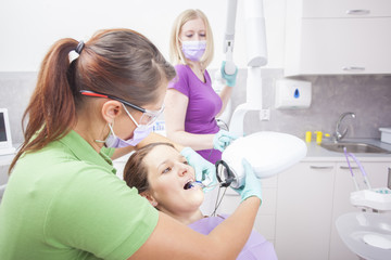 Female dentist and her assistant take jaw x-ray of female patien