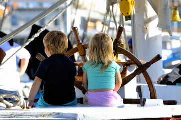 Two young children on the stand of an old wooden sailing
