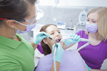 Female dentist and her female assistant working on teeth of wome