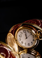 round gold watch with a tracery a red ribbon on a black backgrou