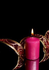 burning candle with ornamental tape on a black background with r