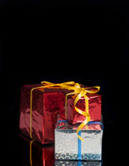 three gifts on a black background with reflection